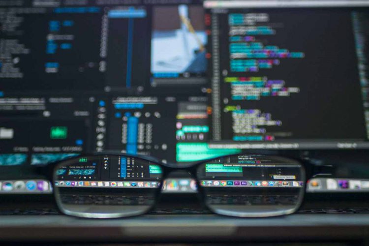 Occhiali in primo piano con dietro Pc infetto da nuovo malware