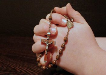 Una persona che prega con un rosario
