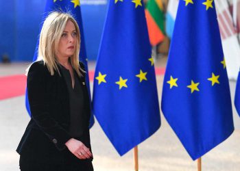 Giorgia Meloni davanti a delle bandiere dell'Unione europea