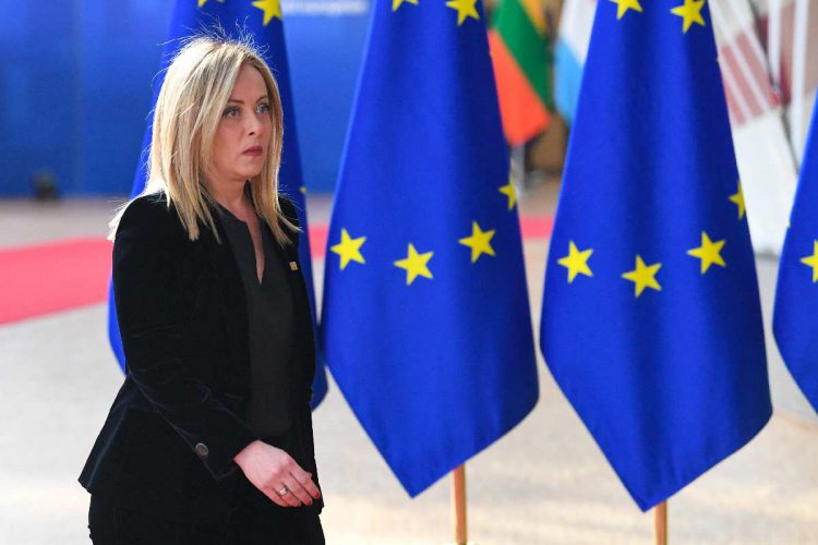Giorgia Meloni davanti a delle bandiere dell'Unione europea