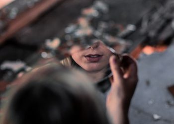 Una ragazza con in mano uno specchio rotto