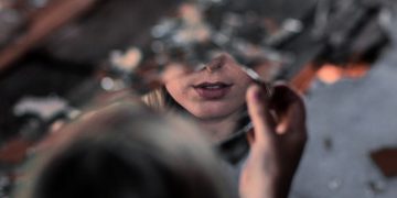 Una ragazza con in mano uno specchio rotto