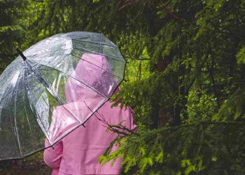 Maltempo, una persona sotto la pioggia con impermeabile e ombrello