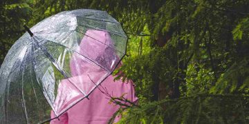 Maltempo, una persona sotto la pioggia con impermeabile e ombrello