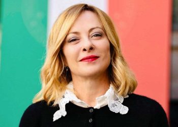 Giorgia Meloni con la bandiera italiana alle spalle