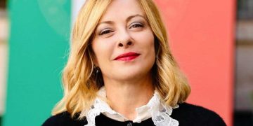 Giorgia Meloni con la bandiera italiana alle spalle