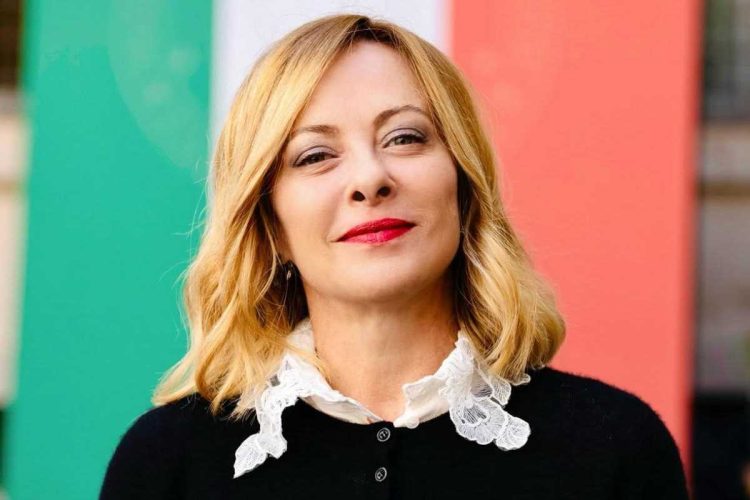 Giorgia Meloni con la bandiera italiana alle spalle