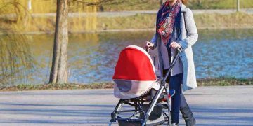 Una donna che cammina spingendo un passeggino