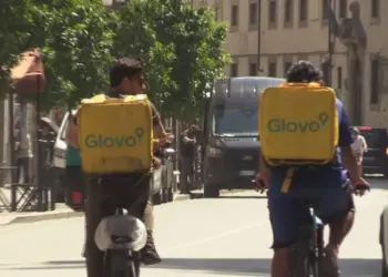 Due rider Glovo che consegnano in bicicletta cibo ordinato sotto al sole cocente