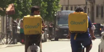 Due rider Glovo che consegnano in bicicletta cibo ordinato sotto al sole cocente