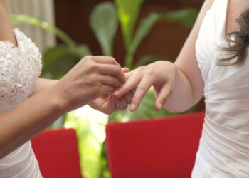 Le mani di due donne intente a scambiarsi gli anelli durante la loro unione civile