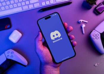 Uomo che tiene in mano uno smartphone con l'app Discord