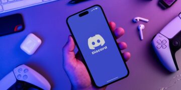 Uomo che tiene in mano uno smartphone con l'app Discord
