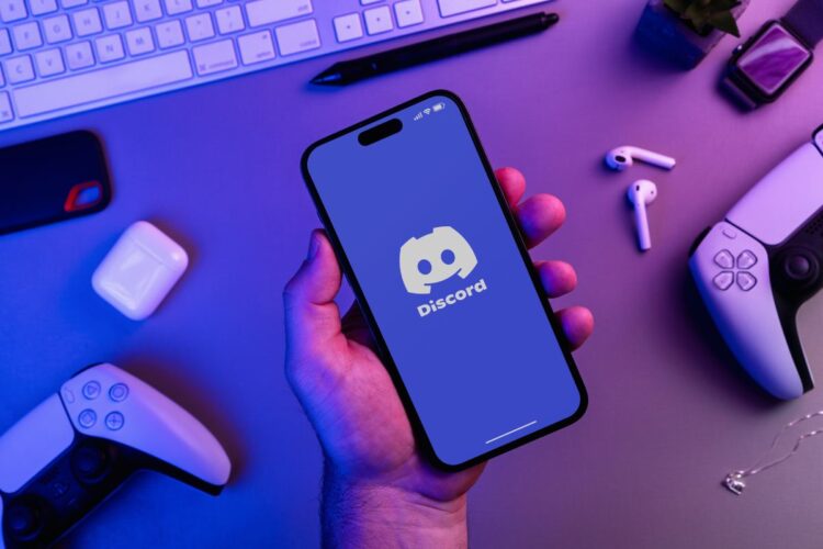Uomo che tiene in mano uno smartphone con l'app Discord