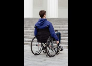 Ragazzo in sedia a rotelle davanti a rampa di scale