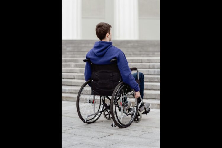 Ragazzo in sedia a rotelle davanti a rampa di scale