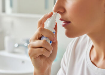 Una persona che sta usando uno spray nasale