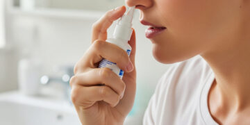 Una persona che sta usando uno spray nasale