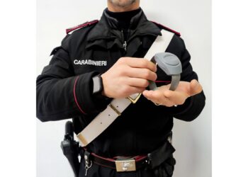 Un carabiniere che tiene in mano un braccialetto elettronico
