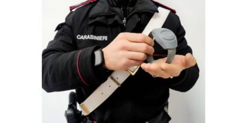 Un carabiniere che tiene in mano un braccialetto elettronico