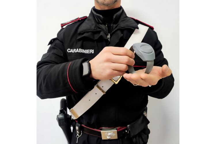 Un carabiniere che tiene in mano un braccialetto elettronico