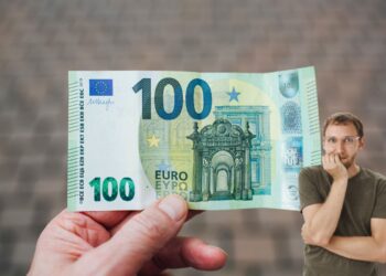 Un uomo con in mano una banconota da 100 euro