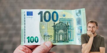 Un uomo con in mano una banconota da 100 euro