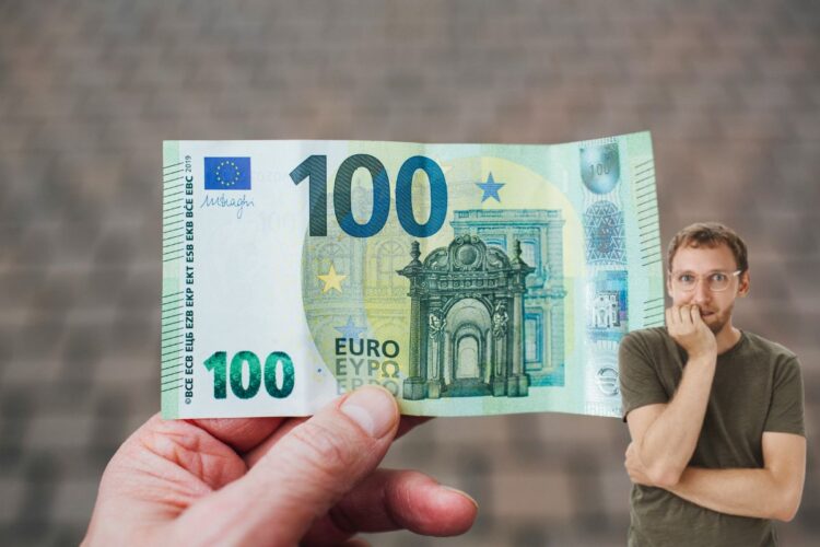 Un uomo con in mano una banconota da 100 euro