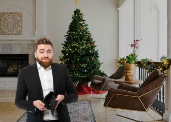 Un uomo con in mano un portafoglio vuoto davanti a un albero di Natale