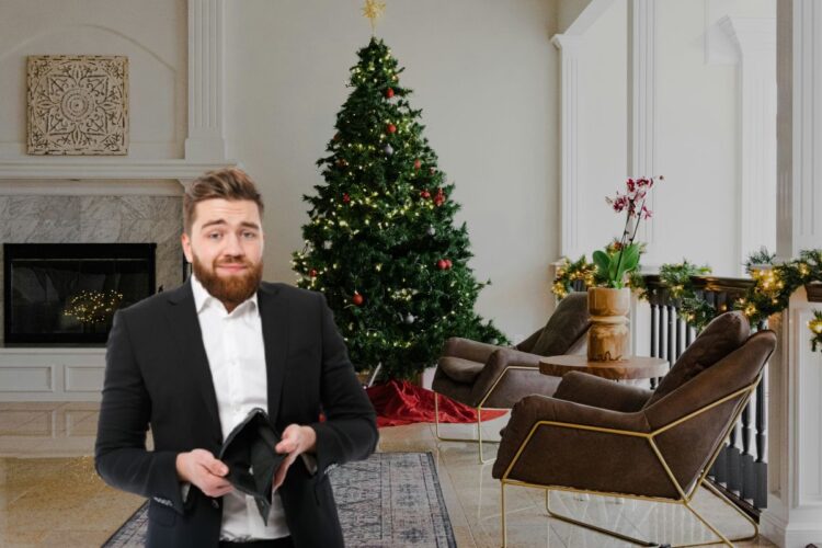 Un uomo con in mano un portafoglio vuoto davanti a un albero di Natale