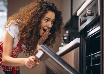 Una donna intenta ad aprire la porta del forno