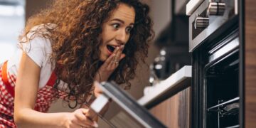 Una donna intenta ad aprire la porta del forno