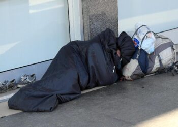 Un clochard addormentato in una strada del centro di Milano