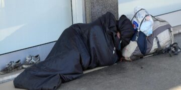 Un clochard addormentato in una strada del centro di Milano