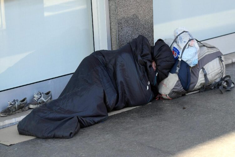 Un clochard addormentato in una strada del centro di Milano