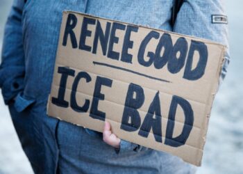 Un manifestante che regge un cartello contro l'ICE