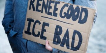 Un manifestante che regge un cartello contro l'ICE