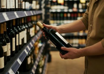 Una persona che sceglie il vino al supermercato