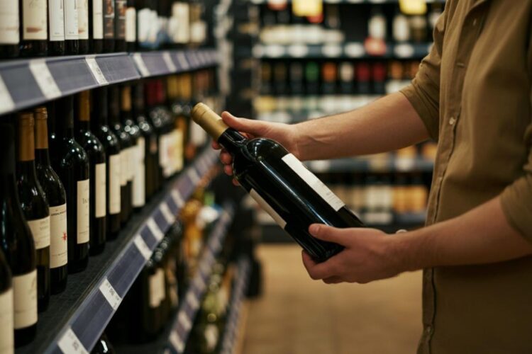 Una persona che sceglie il vino al supermercato