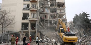 Iranian firefighters and officials work at the site of damaged residential buildings in northern Tehran, Iran, 23 March 2026