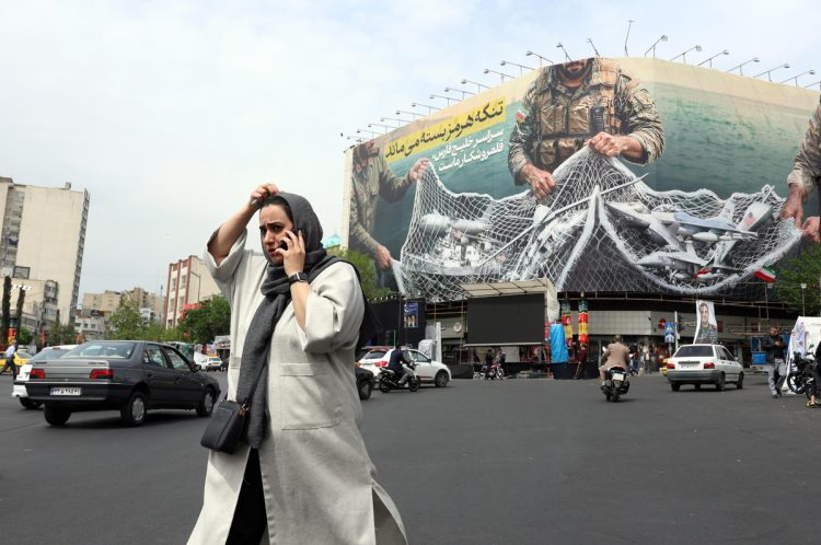 A woman walks next to an anti-US billboard reading in Persian 'The Strait of Hormuz will remain closed' at the Enghelab square in Tehran, Iran, 12 April 2026
