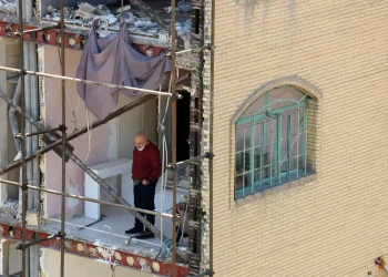 A man looks on from a residential building which was destroyed by US-Israeli airstrikes at the Shahid Broujerdi residential complex in southern Tehran, Iran, 14 April 2026