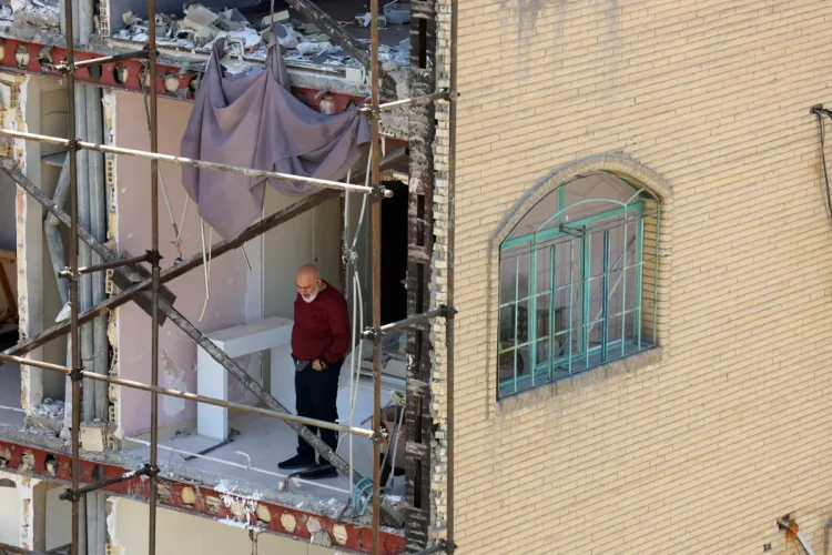 A man looks on from a residential building which was destroyed by US-Israeli airstrikes at the Shahid Broujerdi residential complex in southern Tehran, Iran, 14 April 2026