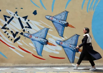 an-iranian-walks-next-to-an-anti-us-and-israel-mural-in-a-street-in-tehran-iran--1200x800.webp