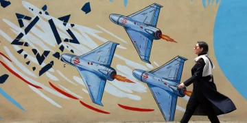 an-iranian-walks-next-to-an-anti-us-and-israel-mural-in-a-street-in-tehran-iran--1200x800.webp