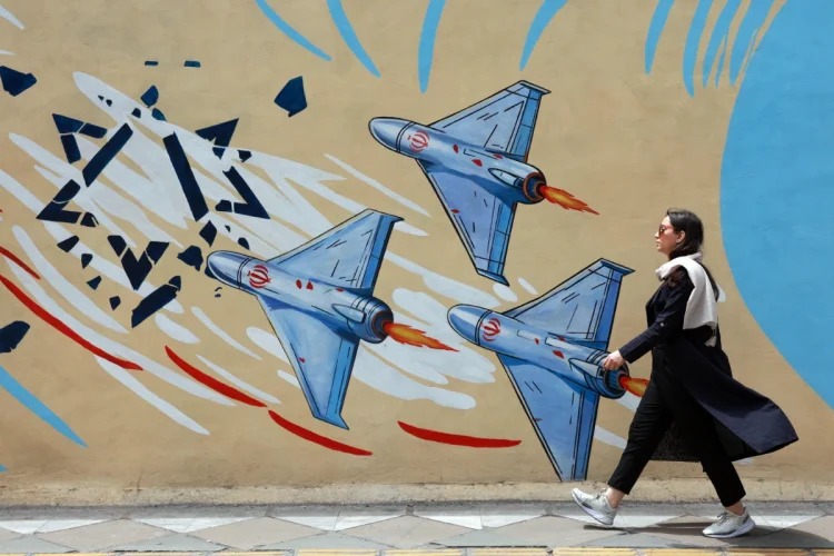 an-iranian-walks-next-to-an-anti-us-and-israel-mural-in-a-street-in-tehran-iran--1200x800.webp