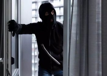 Immagine di un ladro con passamontagna che entra da una finestra con un piede di porco, utilizzata per illustrare il fenomeno dei furti in casa senza segni di scasso