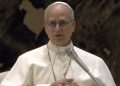 Primo piano di Papa Leone XIV durante un intervento pubblico in Vaticano, con abito bianco papale e microfono, in un’immagine legata al commissariamento dell’ospedale di Padre Pio.
