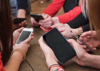 immagine di tanti smartphone tenuti in mano da un gruppo di ragazzi