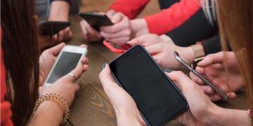 immagine di tanti smartphone tenuti in mano da un gruppo di ragazzi